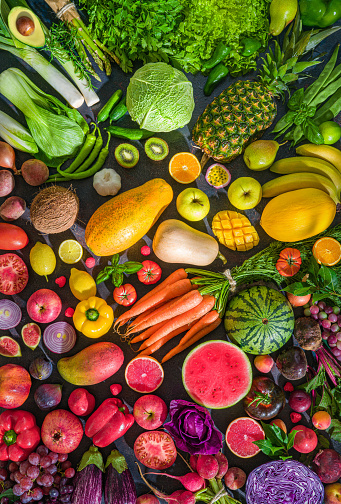 Colorful raw fruits and vegetables varied vegan food, vivid rainbow arrangement full frame background