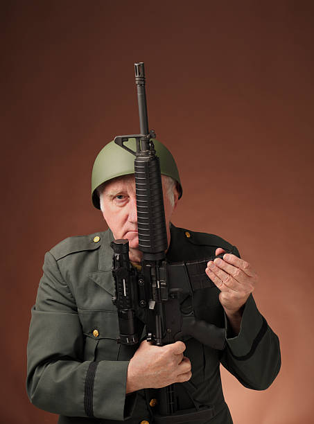 serious mature US veteran soldier with assault rifle  on plain background 