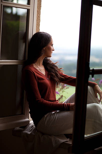 Young woman sitting in window stock photo