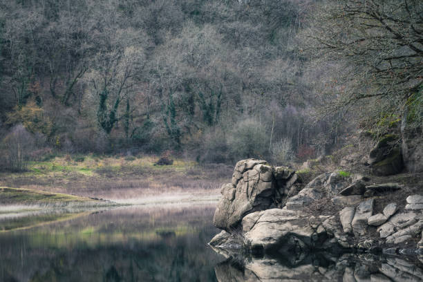 A face shaped rock overlooks the calm river near Portomarin in Lugo Galicia