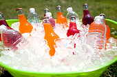 Green bucket filled with water and soda bottles over ice
