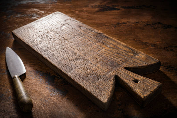 Wooden cutting board or chopping board and kitchen knife on rustic wood table low key kitchenware