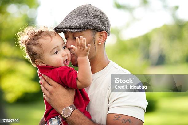 Foto de Feliz Jovem Pai E Bebê Beijando Seu Filho Ao Ar Livre e mais fotos de stock de Família Jovem