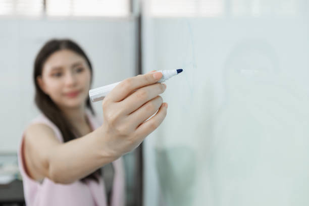 istock Close up pen. Female leader holding pen is writing message on whiteboard. Write presentation at company meeting. 1713075405
