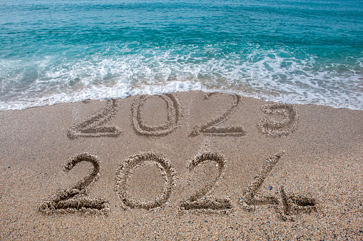 New year 2024 written on sandy beach with waves