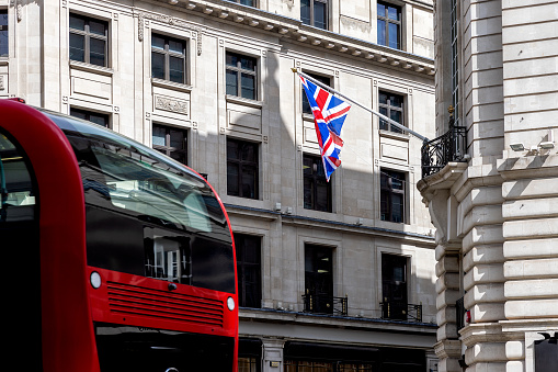 Flag of England with building in the background and bus passing.