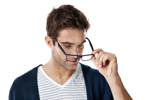 A trendy handsome young man removing his black-rimmed glasses while isolated on white