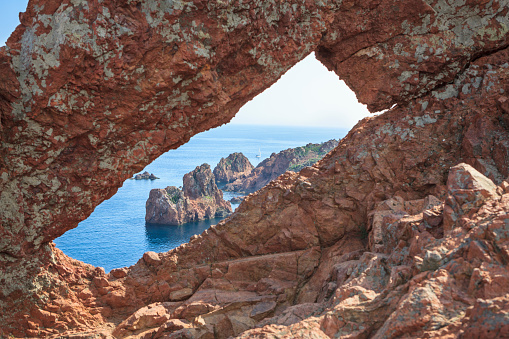 Hole in the stone at the peninsula Cap du Dramont near Frejus. The Cap du Dramont lies at the scenic coast road Corniche d'Or between Cannes and Frejus at the French Riviera below the Massif d'Esterel. It has the same red porphyry stones as the Massif d'Esterel.