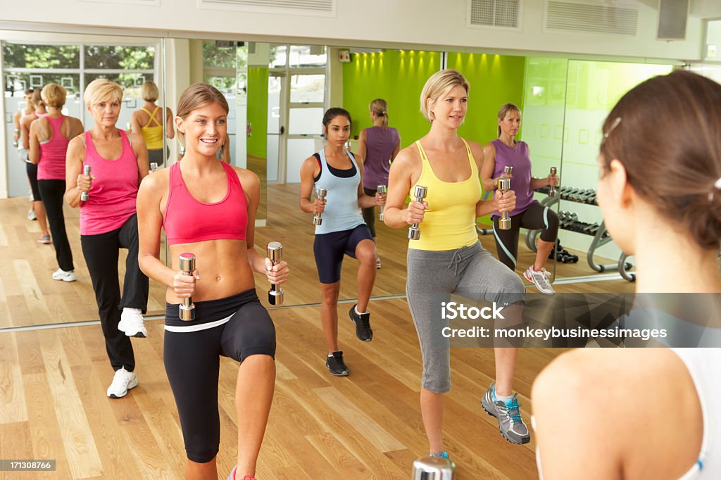 Las mujeres que toman parte en clase de ejercicios con pesas del gimnasio - Foto de stock de Clase de ejercicio libre de derechos