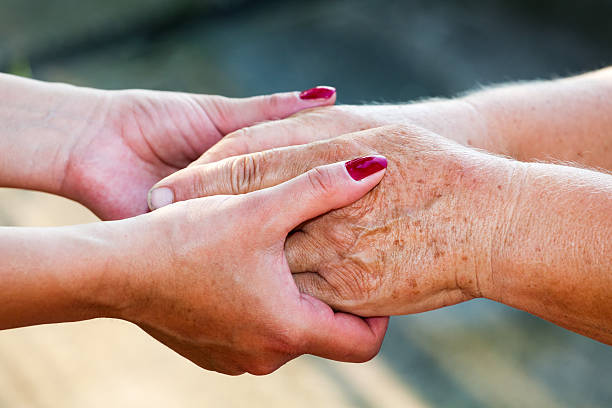 Young and senior women holding hands stock photo