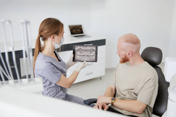 Portrait of young female dentist standing by mid adult man in clinic. Female dentist repairing patient tooth in dental ambulant Portrait of young female dentist standing by mid adult man in clinic ambulant patient stock pictures, royalty-free photos & images