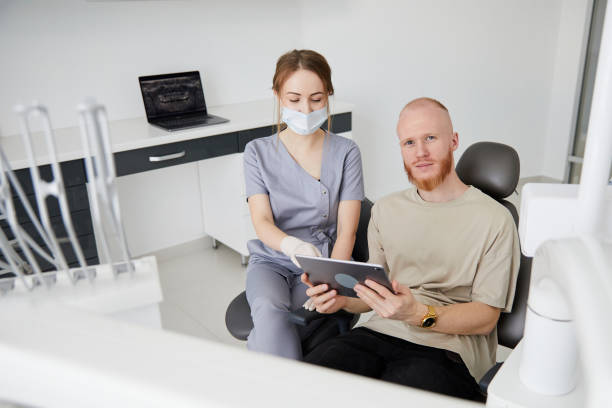 retrato de una joven dentista de pie junto a un hombre adulto en la clínica. dentista hembra reparando diente de paciente en ambulant dental - ambulant patient fotografías e imágenes de stock