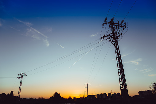 Sunset silhouette of electric towers in an area under construction, copy space.