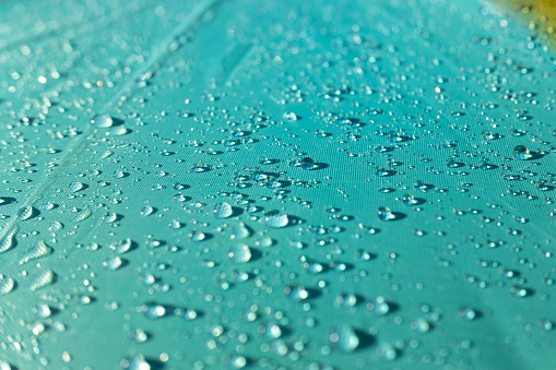 Detail of water drops on a plastic fabric colored in the sun.