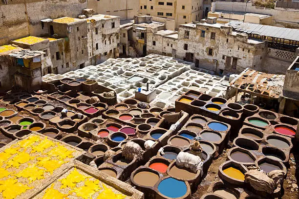 Workers  and dyeing in red hides in the vats of Fez tanneries, Morocco.