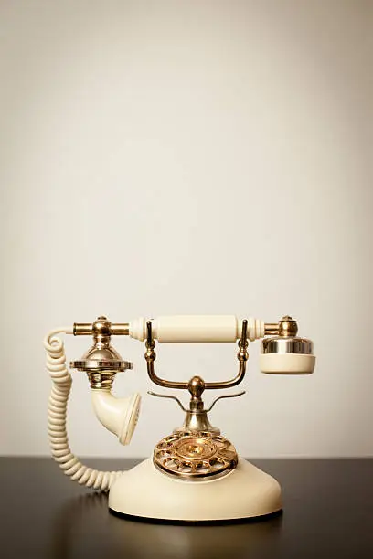 "Slightly desaturated color image of an antique, Victorian-style rotary telephone sitting on a table, with copy space."