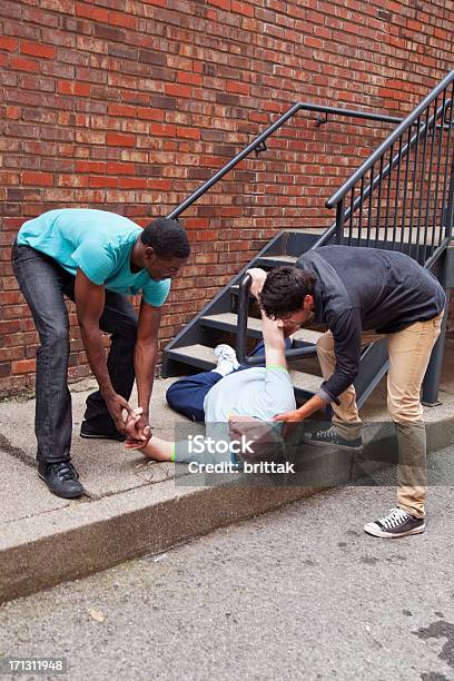 Two Young Men Help Senior Who Has Fallen Down Stairs Stock Photo - Download Image Now