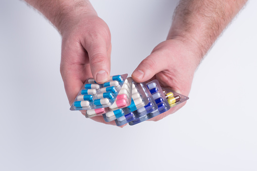 Close-up of hand holding medication blister packs of tablets and capsules against .Colorful pills and medicines in the hand.