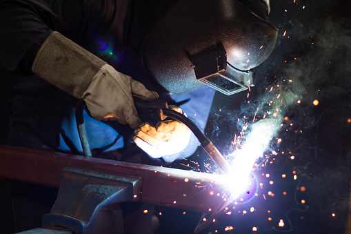 Welders wear protective equipment to prevent sparks from welding steel.