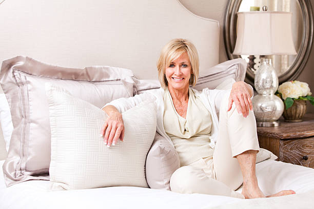 elegante donna matura è appoggiato su un letto. - mature women beautiful senior women menopause foto e immagini stock