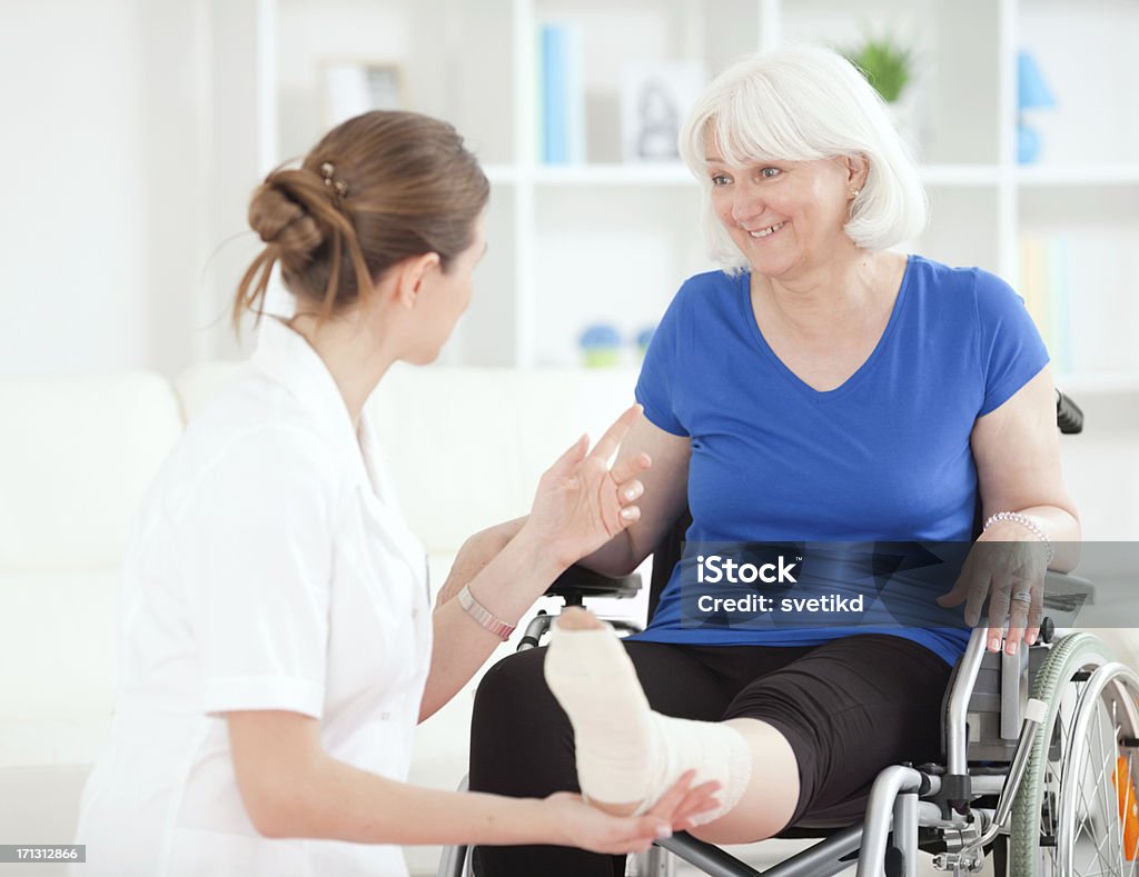 Doctor examining injured leg of senior woman. Female doctor or physician examining injured leg of senior woman indoors.See more LIFESTYLE and MEDICAL images with this SENIOR WOMAN. Click on image below for lightbox. 60-64 Years Stock Photo
