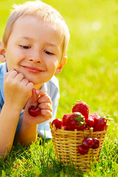 Kid lying down on the grass with strawberries stock photo