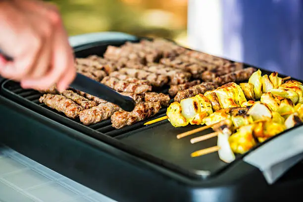 Barbeque electric grill with cevapcici and chicken skewers.