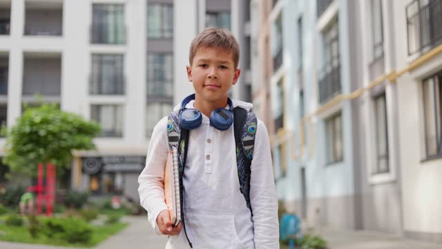 Young Boy Student Going to School Wearing a Backpack and Holding a Notebook. Modern Handsome School Guy Walking after Studying. Back to School. School and Children Concept.