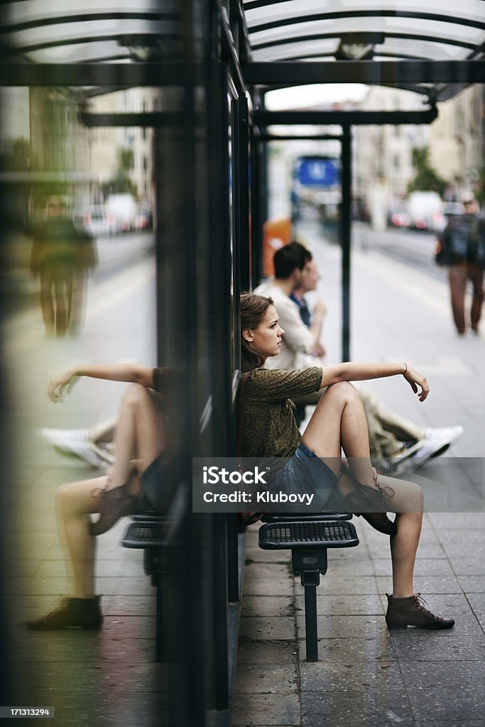 Молодая женщина на автобусной остановке - Стоковые фото Автобусная остановка роялти-фри