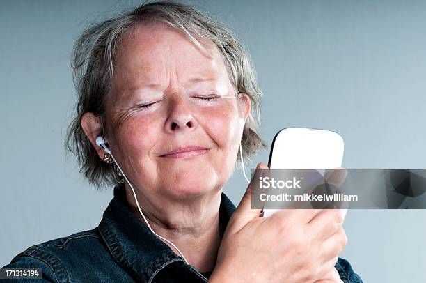 Senior Woman Listens To Music On Her Phone Stock Photo - Download Image Now - Podcasting, Senior Adult, Audiobook