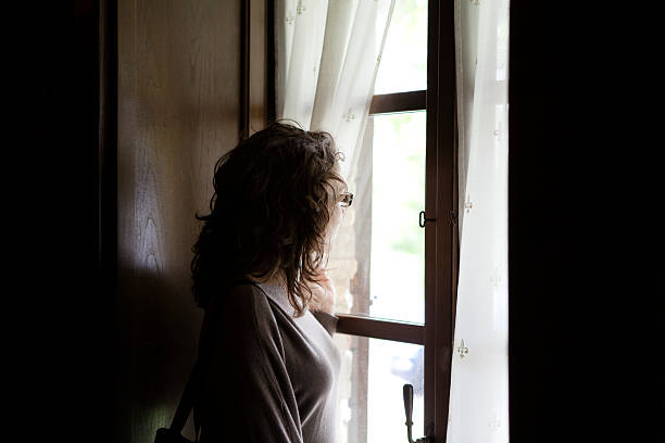 istock Pensive woman looking through a window 171314278