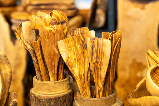 Various wooden cooking spoons and spatulas in a container made of wood for a natural kitchen and against plastic