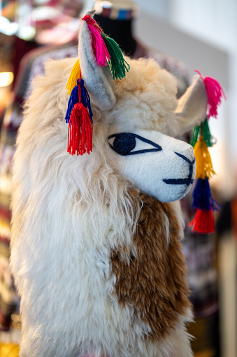 A llama or alpaca made of fabric with big eyes and colorful fringes on the hair