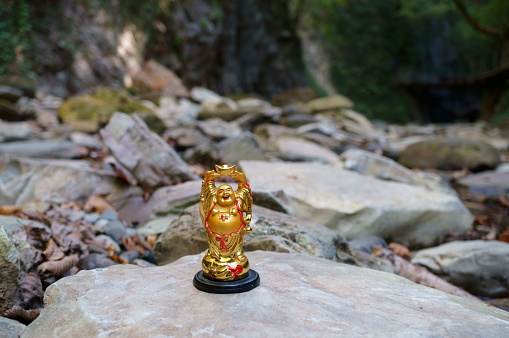 A figure of a smiling Buddha on the background of a mountain.