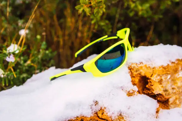 Trendy yellow sports sunglasses on snow during a hiking excursion
