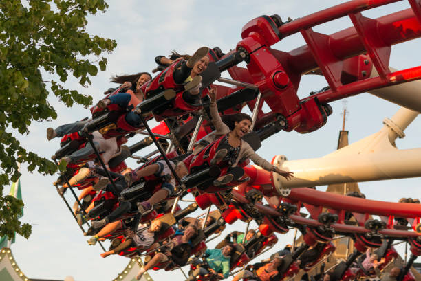 Ballycastle, UK - August 26th, 2024:  brave amusement park customers flying high into the air on the mechanical arm of a thrill seeking theme park ride.