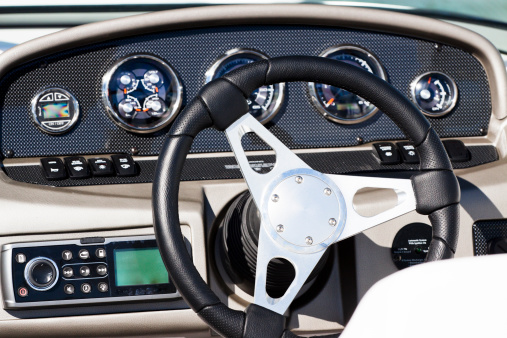 Luxury speedboat control panel with steering wheel, front view, full frame horizontal composition