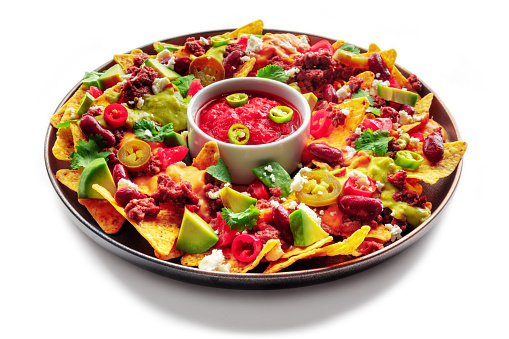 Loaded nachos. Mexican nacho chips with beef, guacamole sauce, cheese salsa, beans and peppers, isolated on a white background