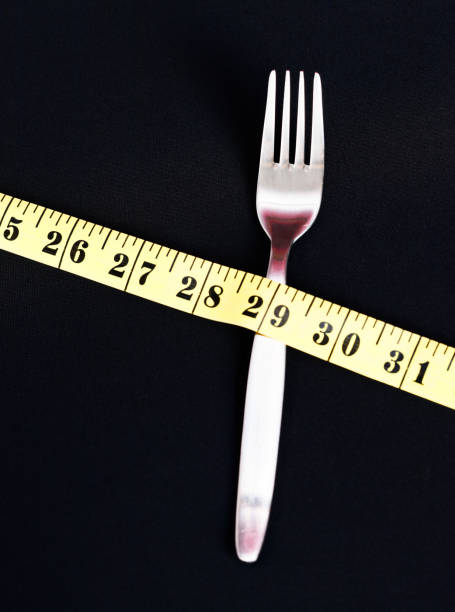 istock Tape measure lying diagonally over fork on black background 171315600