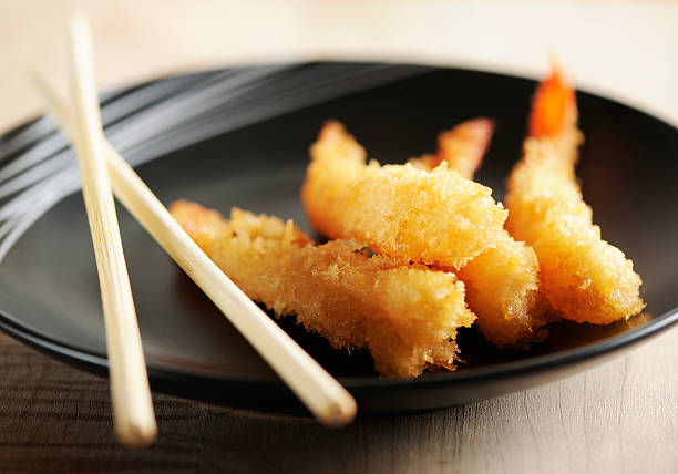 Tempura shrimps Fried tempura shrimps and chopsticks in a black plate on  a wooden background. Tempura Prawns stock pictures, royalty-free photos & images