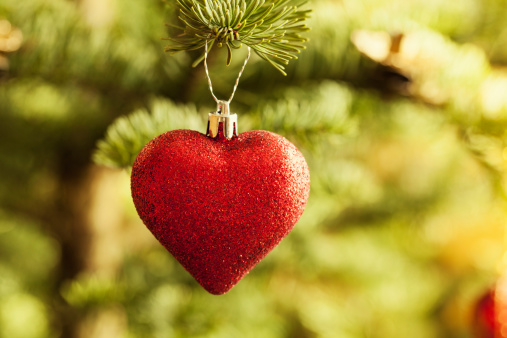 glittery christmas bauble in heart shape hanging in christmas tree