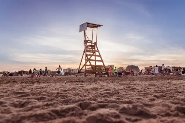 Valencia, Spain - June 23, 2019: Watchtower on the beach, without lifeguard, on a beach with children playing at sunset.