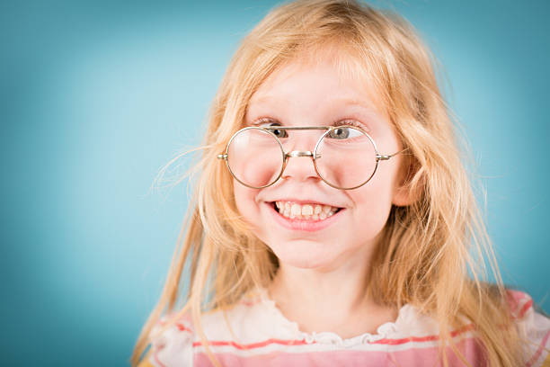 маленькая девочка, что делает дурачусь лицо, в то время как nerdy очки в винтажном стиле - child cross eyed nerd eyewear стоковые фото и изображения