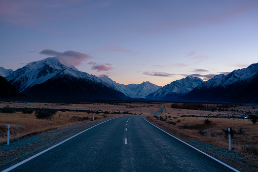 With dawn approaching to the east, the sky lightens above the road to Mt Cook on New Zealand's South Island.