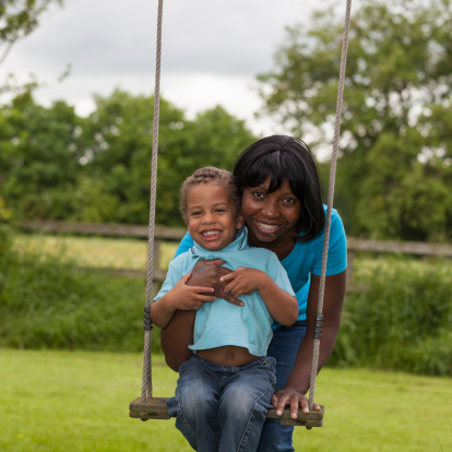 A mother and her son playing together at the swings.