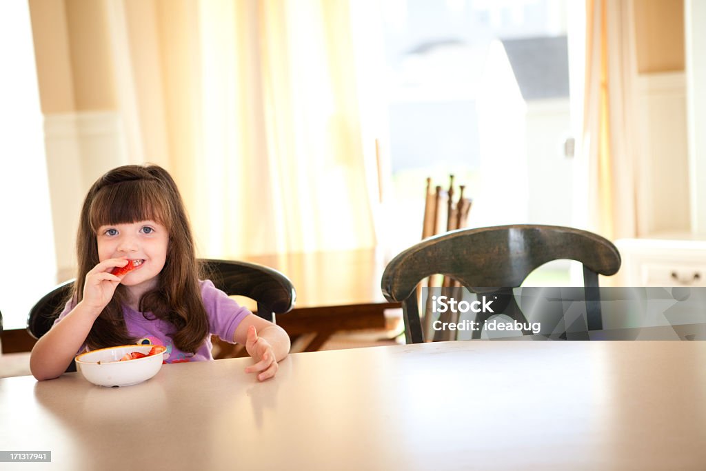 Dziewczynka jedzenie owoców na ladzie w jej kuchni - Zbiór zdjęć royalty-free (2-3 lata)