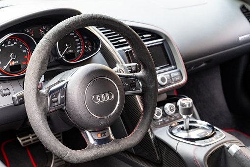 Audi R8 V10 Plus sports car dashboard. The Audi R8 is a mid-engine, two-seater sports car manufactured and marketed by the German automobile manufacturer Audi. The Audi R8 V10 Plus is a high-performance variant of the Audi R8 sports car.