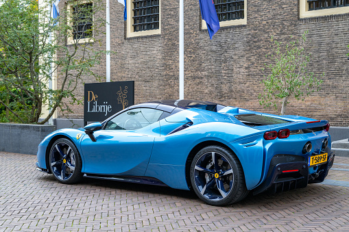 Ferrari SF90 sports car in light blue parked on the street in Zwolle. The Ferrari SF90 Stradale, unveiled in 2019, is a hybrid sports car and the first series-production Plug-In Hybrid Electric Vehicle (PHEV) from Ferrari. The SF90 Stradale is powered by a 4.0-liter twin-turbocharged V8 engine coupled with three electric motors – two at the front and one at the rear.