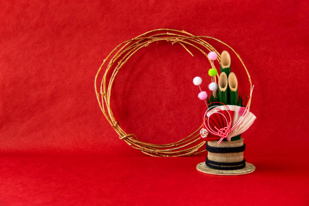 赤い背景に日本の新年のお祝いのための竹の装飾、金色の円と扇子と餅の花。