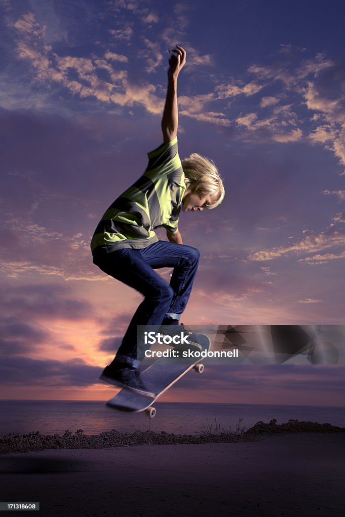 Ragazzo facendo Skateboard Ollie al tramonto - Foto stock royalty-free di Andare sullo skate-board